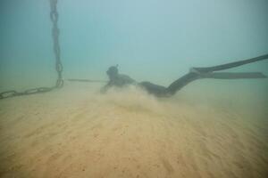 Anonymous diver with harpoon hunting in deep sea photo