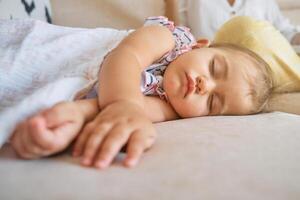 Toddler covered with blanket sleeping on sofa photo