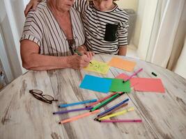 Unrecognizable grandmother and boy drawing on paper photo
