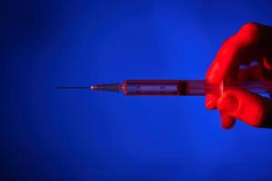 Anonymous person with syringe in neon lighting photo