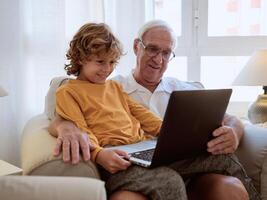 Cheerful grandson with grandfather browsing netbook photo