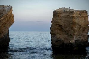 a bay between two rocks on the sea. two rocks on the sea through which a view of the sunset sea opens. sandstone rocks. the sea is calm, the sky is mangent colors photo