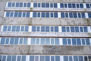 The facade of an industrial building made of white brick and concrete slabs. The building has many white plastic windows. A sign on the side of a building. High quality photo. photo