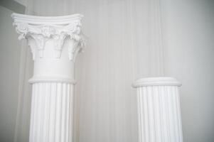 element of antique column in interior. photo zone for photo sessions. two white columns are located in interior. white chiffon fabric is planted.