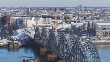 Antenne Aussicht von Riga, Lettland, zeigen das Daugava Fluss, gewölbt Eisenbahn Brücke, National Bibliothek, und alt Stadt, Dorf mit ein schleppend schwenken über das Stadtbild. video