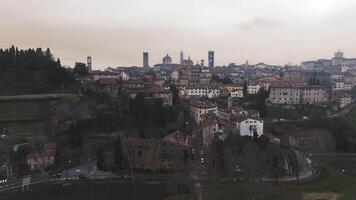 Panoramic view of Bergamo's historic skyline with bell towers and domes, transitioning to green hills, winding roads, and subtle motion of cars. video