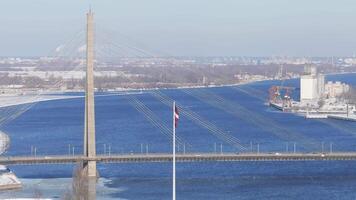 Aerial view of Riga on a clear winter day, showing the Daugava River, a bridge, the National Library of Latvia, and the port area with cranes. video