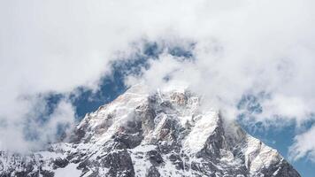 Matterhorn peak viewed from the Cervino side in Italy, with clouds moving dynamically across snow covered slopes and a vibrant blue sky. video