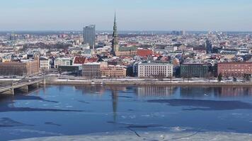 Aerial view of Riga, Latvia, showing the Daugava River with ice, a busy bridge, Old Town landmarks and a clear blue sky. video