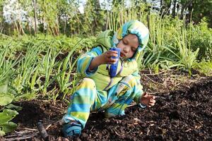 Funny Little Boy Playing In The Garden. photo