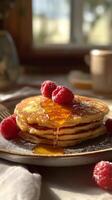 A stack of fluffy pancakes topped with fresh raspberries and drizzled with golden syrup. Cozy breakfast. Vertical image photo