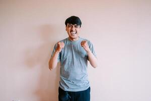 Elated young man celebrating success with clenched fists indoors photo