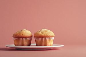 Two Vanilla Cupcakes on Plate Against a Soft Pink Background photo