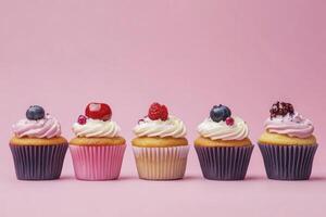 Row of Cupcakes with Frosting and Berries Against a Pink Background photo