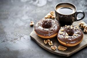 Enjoying Fresh Coffee and Chocolate Donuts with Walnuts on Dark Table photo
