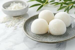 Serving of Mochi on Plate with Rice Bowl and Bamboo Leaves photo