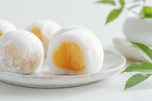 Delicious Mango Mochi Close-up on Plate with Green Leaves Decoration photo