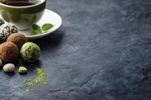 Enjoying Tea and Healthy Chocolate Truffles on a Dark Textured Surface photo