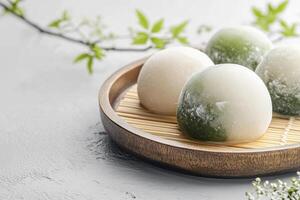 Mochi Rice Cake Treats on Wooden Plate with Green Leaves Arrangement photo