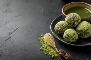 Serving Matcha Tea and Chocolate Truffles with Bamboo Whisk on Dark Background photo