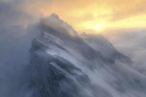Snowy Mountain Peak Emerging From Clouds at Sunrise photo