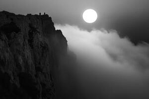 People Standing on Mountain Peak Overlooking Clouds with Sunlight in Monochrome photo