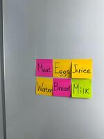 Multicolored sticky notes with list of products for refrigerator photo