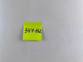 Phone number is written with marker on bright sticky note photo