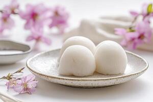 Three Mochi Rice Cakes on a Plate with Pink Blossom Background photo