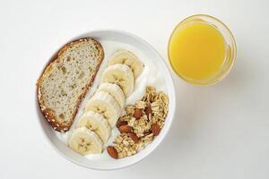 Healthy Breakfast Bowl with Yogurt, Banana, Bread, Granola and Orange Juice photo