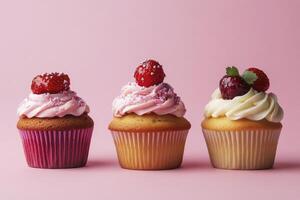 Three Cupcakes with Frosting and Berries on a Pink Background photo