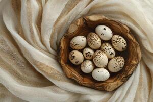 Speckled Quail Eggs in Wooden Bowl on Soft Textured Fabric photo