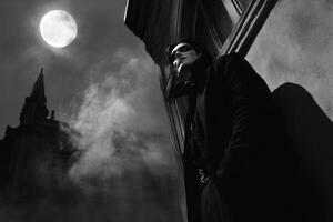 Man in Dark Coat at Night with Gothic Building and Moon photo