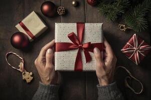 Holding Christmas Gift with Red Ribbon on Dark Wood Table Overhead photo