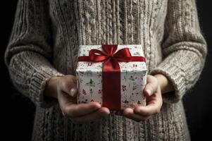 Holding Wrapped Gift Box with Red Ribbon in Knitted Sweater photo