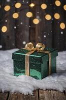 Green Gift Box with Gold Ribbon in the Snow with Bokeh Lights photo