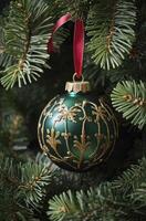 Elegant Green Christmas Ornament with Gold Decoration Hanging on Tree Branch photo