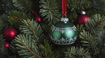 Green Christmas Ornament Hanging on Fir Tree with Red Decorations photo