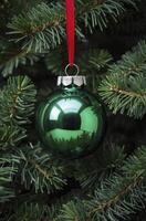 Hanging Green Christmas Ornament on a Tree with Red Ribbon Decor photo