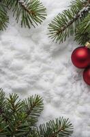 Red Christmas Ornaments and Pine Tree Branches on Fresh Snow Background photo