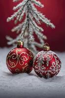 Festive Red Christmas Ornaments on Snow with Pine Bough Background photo