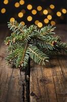 Evergreen Branch on Rustic Wooden Table with Warm Bokeh Lights photo