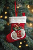 Hanging Christmas Stocking Ornament on Tree with Blurred Lights Background photo