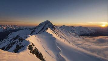 Snowy Mountain Peaks at Sunrise with Golden Light and Cloud Inversion photo