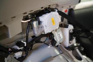 View of a car interior without decorative elements, the rear passenger seatbelt retractor unit in a car, wiring, and other safety-related modules photo