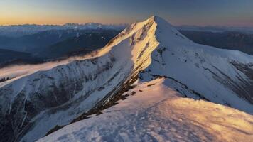 Snowy Mountain Peak at Sunrise with Golden Light and Distant Ranges photo