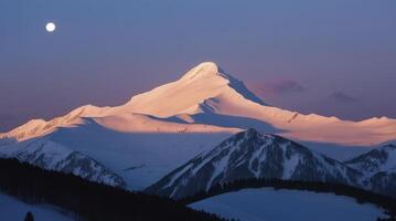 Snowy Mountain Peak at Dusk with Moon in Clear Winter Sky photo