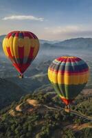 Hot Air Balloons Flying Over Green Landscape with Mountain Views photo