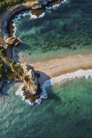 Aerial View of Coastal Beach with Clear Water and Rocky Cliffs photo