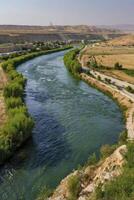 Scenic River Landscape with Hills and Vegetation Under a Clear Sky photo